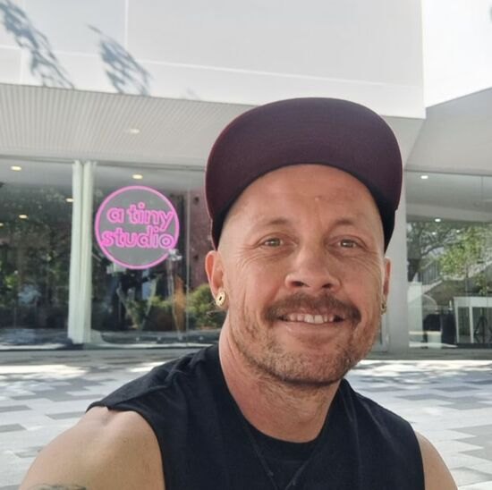 Don, owner of A Tiny Studio, outside the studio's neon sign
