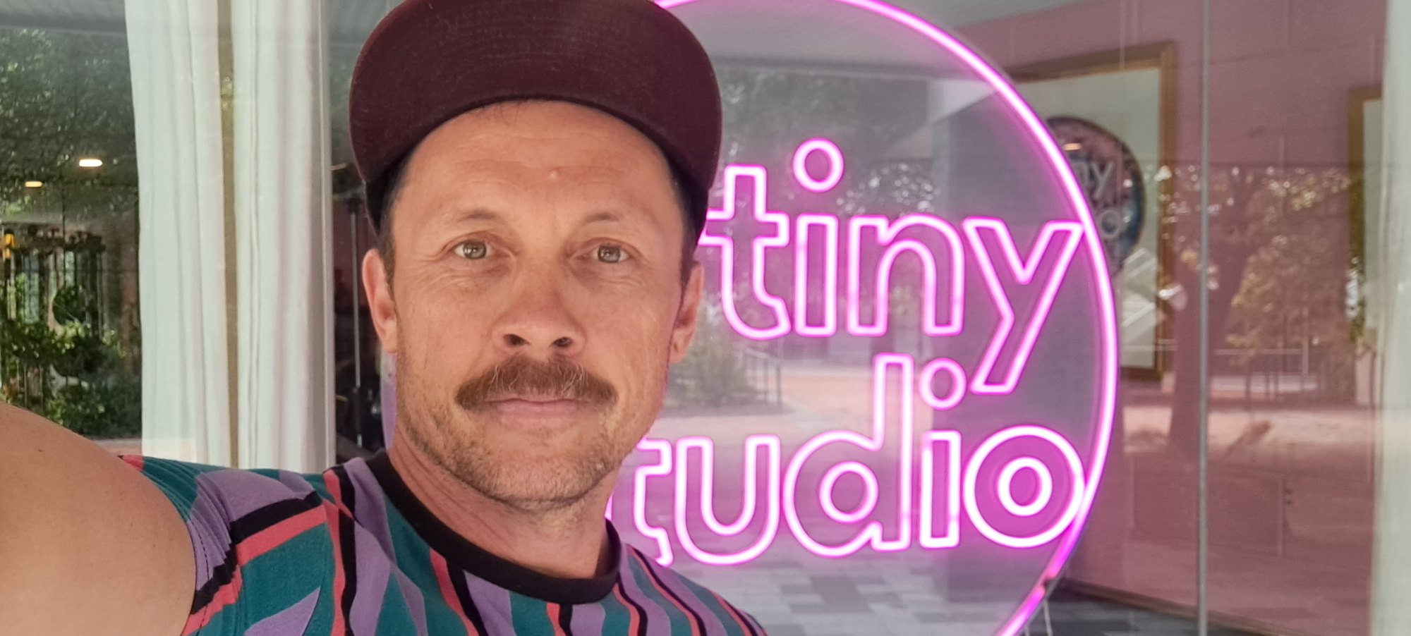 Don outside the A Tiny Studio window with its pink neon sign