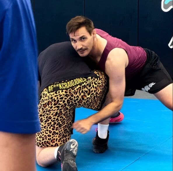 Nick coaching a wrestling move on the studio mats