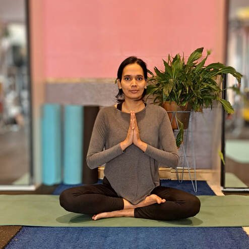 Amrita in a seated yoga pose on a mat