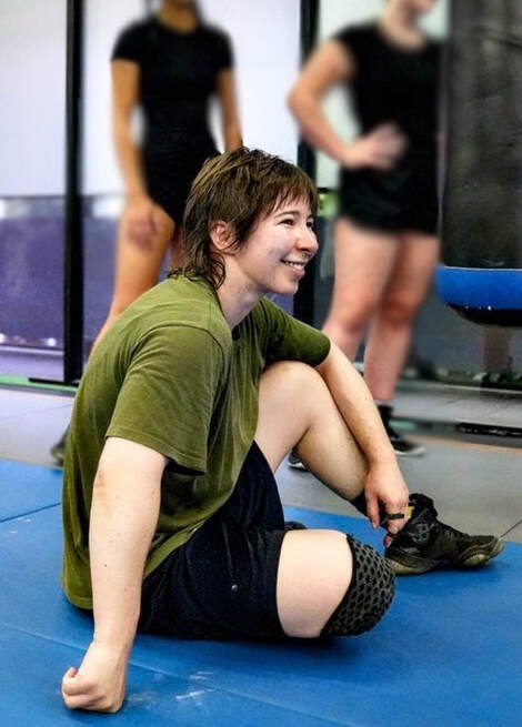 Charlie, personal trainer, sitting on the studio mats